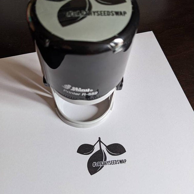 Round self-inking stamp on top of white paper with a black ink impression