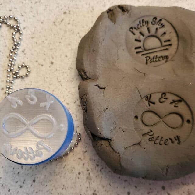 Makers mark stamp next to clay with impression